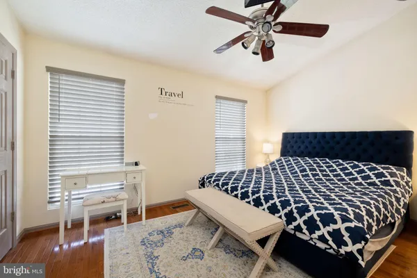 a bedroom with a bed and dresser with wooden floor