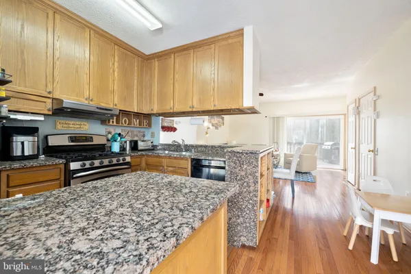 a kitchen with stainless steel appliances granite countertop a refrigerator a stove and a wooden cabinets
