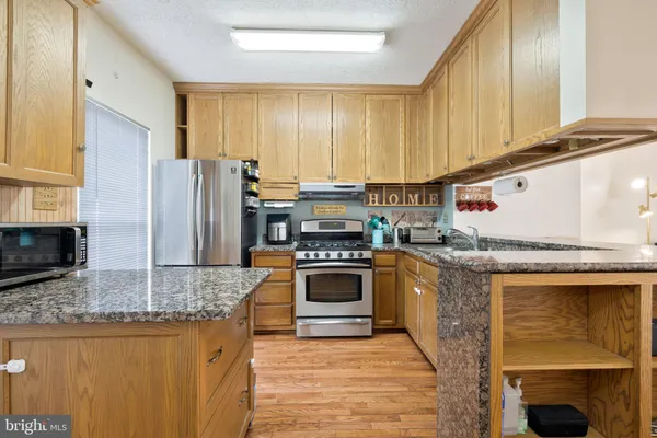 a kitchen with stainless steel appliances granite countertop a stove refrigerator sink and microwave
