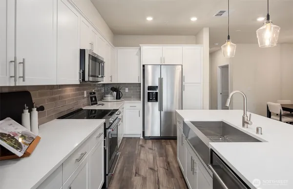 a kitchen that has a sink a center island stainless steel appliances and cabinets