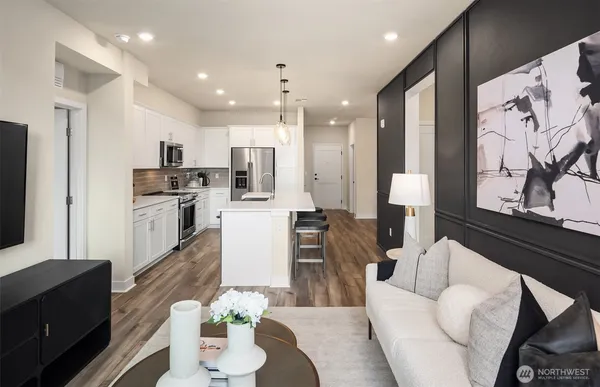 a living room with stainless steel appliances furniture a couch and a kitchen