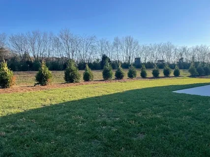 a large white kitchen with granite countertop a stove a sink a refrigerator and white cabinets with wooden floor