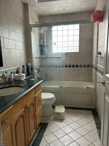 a bathroom with a granite countertop sink a toilet a mirror and bathtub