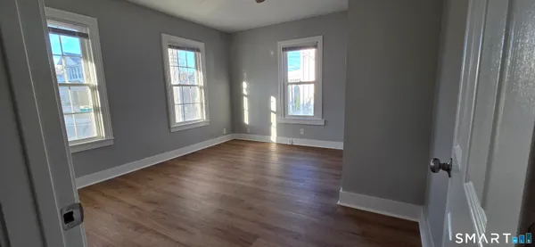 a view of an empty room with wooden floor and window
