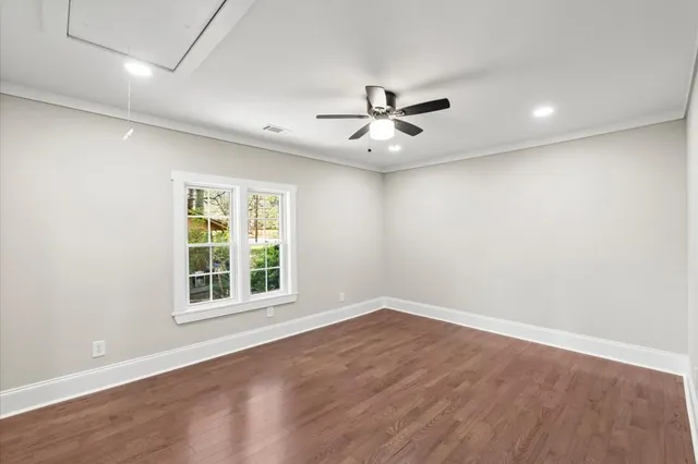 a view of empty room with wooden floor and fan