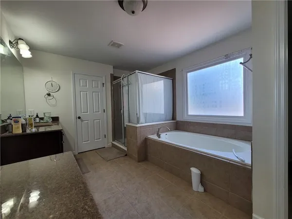 a spacious bathroom with a tub a double vanity sink and mirror