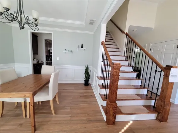 a view of a dining room with wooden floor a chandelier a wooden table and chairs