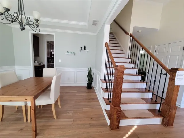 a view of a dining room with wooden floor a chandelier a wooden table and chairs