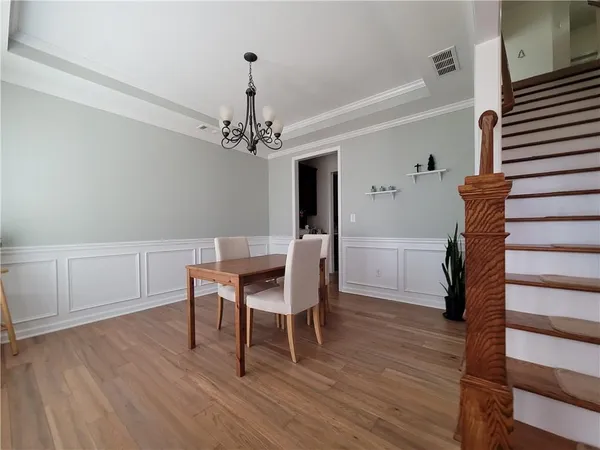 a dining room with wooden floor a chandelier a wooden table and chairs