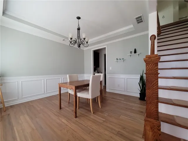a dining room with wooden floor a chandelier a wooden table and chairs