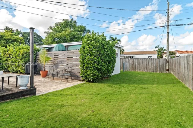 a view of a backyard with plants and large trees with wooden fence