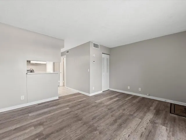 a view of an empty room with wooden floor