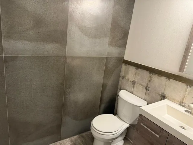 a white toilet sitting next to a bathroom sink and vanity