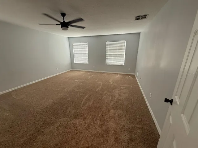 an empty room with a windows and a ceiling fan