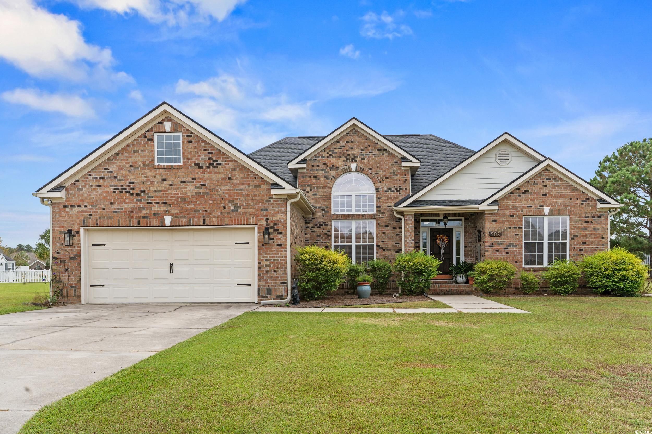 Traditional home featuring a front yard, concrete driveway, brick siding, a garage, and a shingled roof