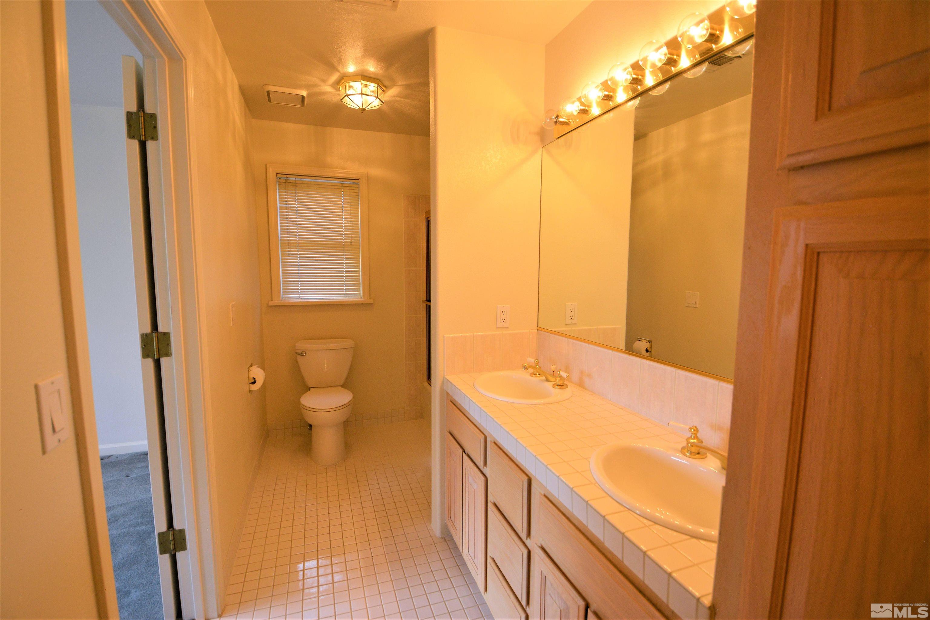 545 Skyline Boulevard Reno, NV 89509 - Photo 28 of 39 a bathroom with a granite countertop sink a toilet and shower