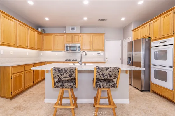 a kitchen with stainless steel appliances kitchen island granite countertop a refrigerator and cabinets