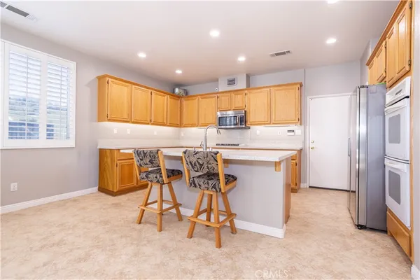 a kitchen with stainless steel appliances kitchen island granite countertop a refrigerator and microwave
