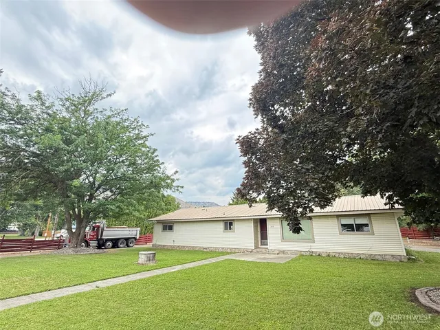 a white house with a big yard and large trees