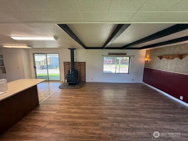 a view of an empty room with window and wooden floor