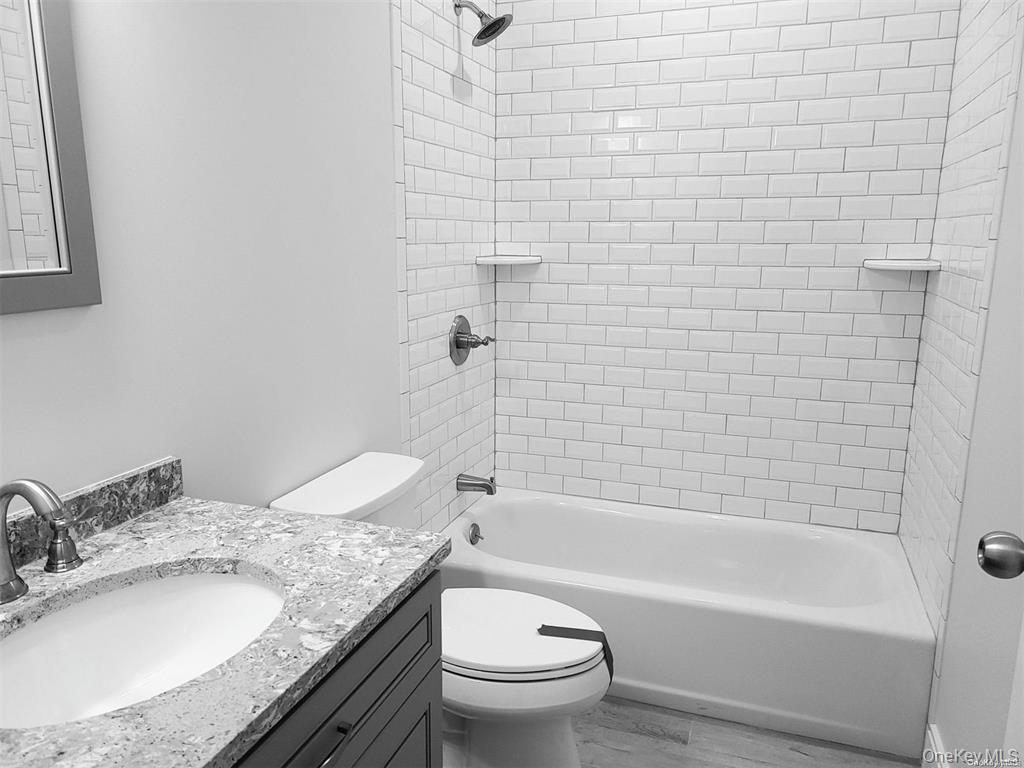 262 East Main Street, Unit D Babylon, NY 11702 - Photo 12 of 17 a bathroom with a granite countertop toilet a sink and a bathtub