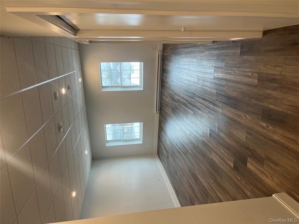 262 East Main Street, Unit D Babylon, NY 11702 - Photo 13 of 17 an empty room with wooden floor and windows
