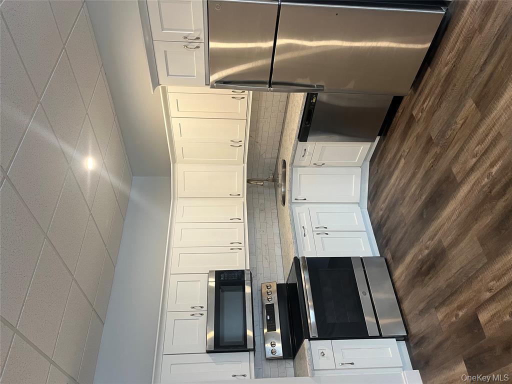 262 East Main Street, Unit D Babylon, NY 11702 - Photo 16 of 17 a kitchen with granite countertop a refrigerator stove and microwave