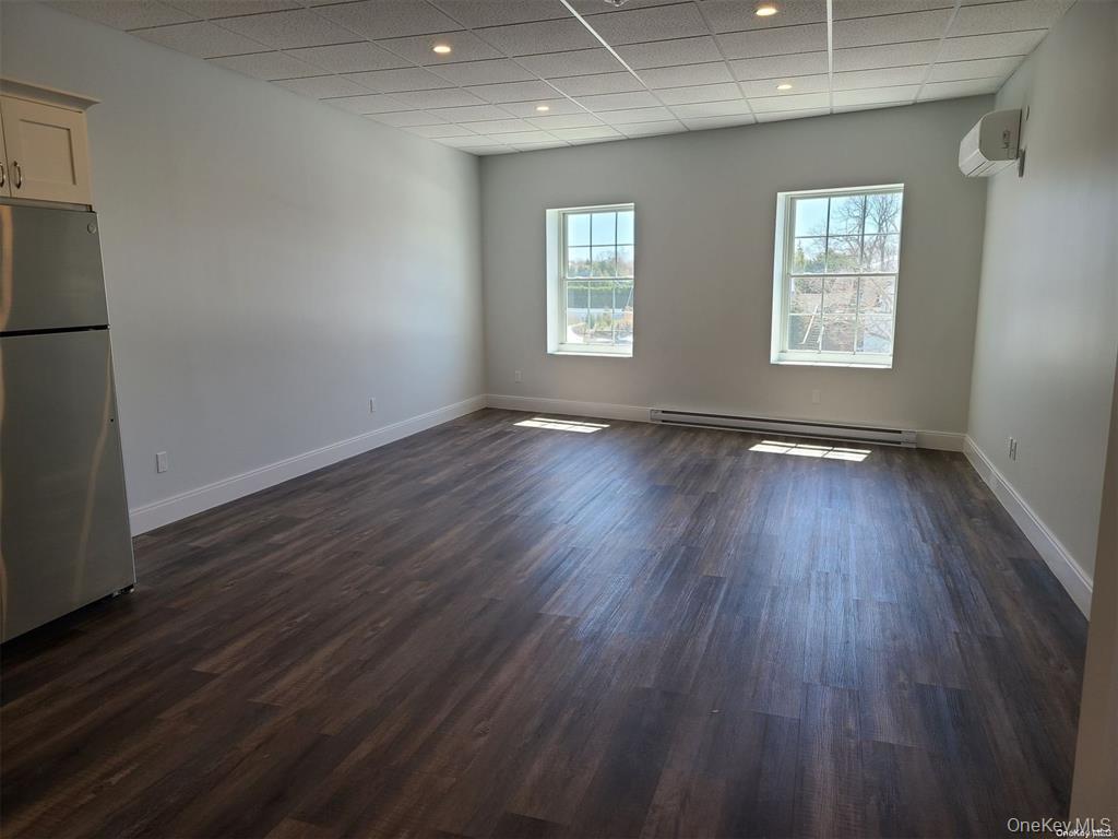 262 East Main Street, Unit D Babylon, NY 11702 - Photo 10 of 17 an empty room with wooden floor and windows