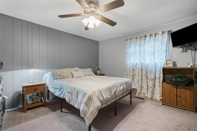 a bedroom with a bed and a flat tv screen on dresser