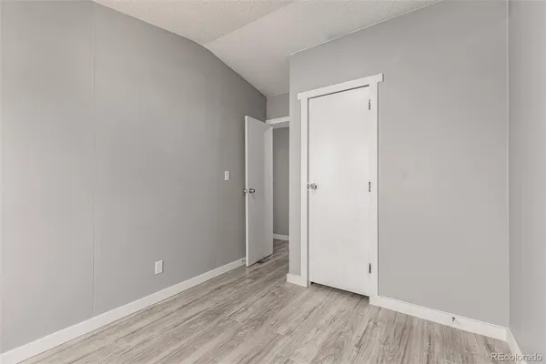 a view of an empty room with wooden floor and closet