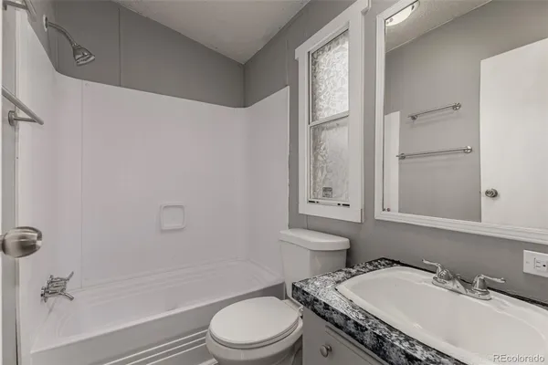 a bathroom with a granite countertop sink toilet a mirror and shower