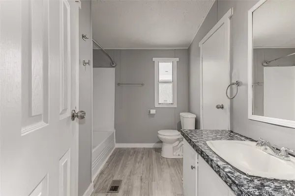 a bathroom with a granite countertop sink toilet and shower glass cabinet