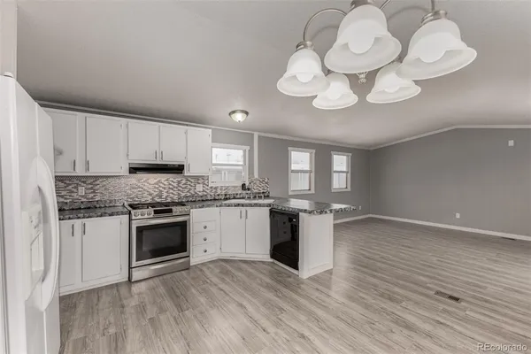 a kitchen with a stove and white cabinets with wooden floor