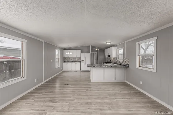 a large white kitchen with kitchen island a sink wooden floor and a refrigerator