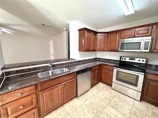 a kitchen with stainless steel appliances granite countertop a sink stove and microwave