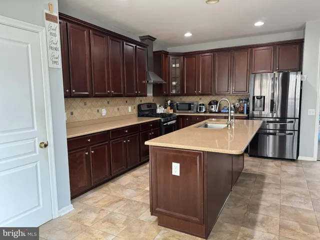 a kitchen with wooden cabinets stainless steel appliances a sink and a refrigerator