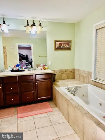 a spacious bathroom with a tub sink and mirror