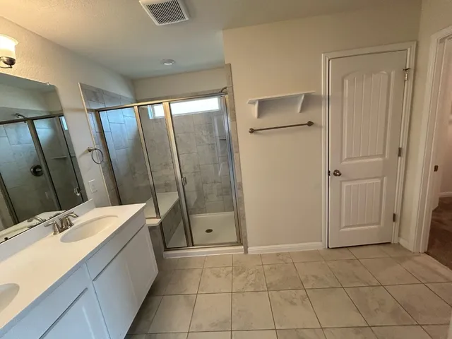a bathroom with a granite countertop sink a mirror and a shower