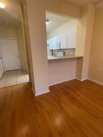 a view of kitchen and empty room with wooden floor