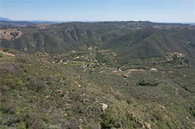 a view of a dry field with mountains in the background