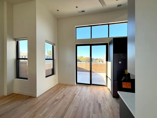 an empty room with wooden floor closet and windows