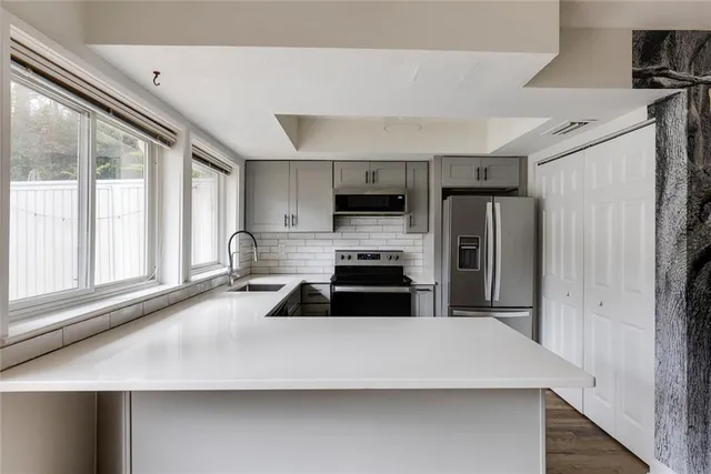 a kitchen with a sink a stove a microwave cabinets and a window