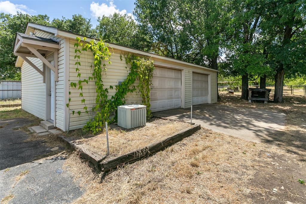 1346 South Reno Road Springtown, TX 76082 - Photo 21 of 24 Detached two-car garage with horizontal siding, two overhead doors, a side entry door with an awning, and a visible HVAC unit