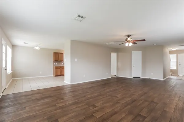 a view of an empty room with a chandelier fan and a window