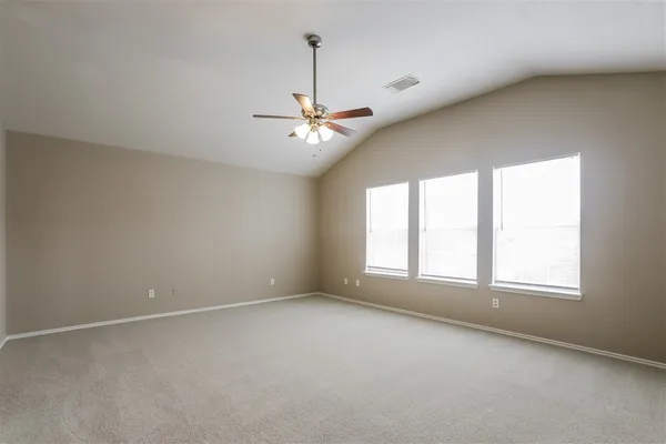 an empty room with a chandelier fan and windows