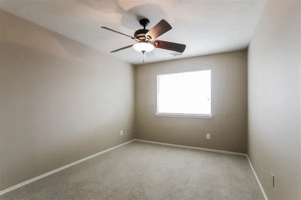 an empty room with windows and fan