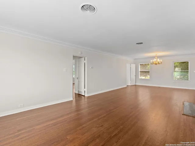 an empty room with wooden floor fireplace and windows