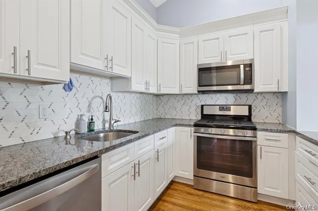 a kitchen with granite countertop white cabinets and a stove