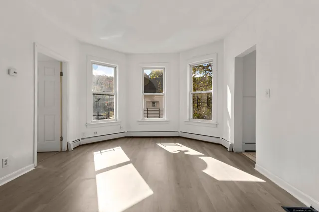 an empty room with wooden floor and windows