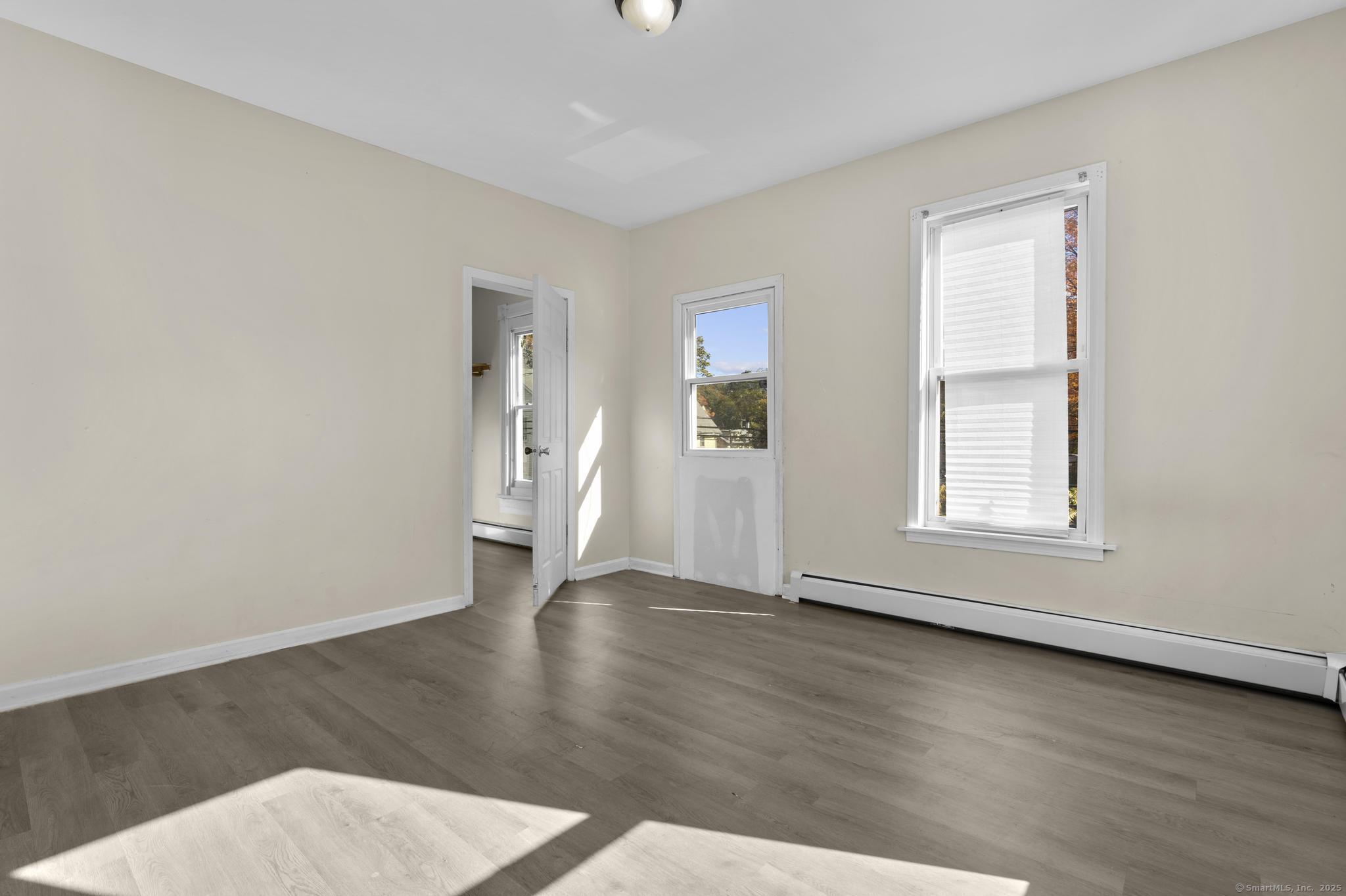 141 Crown Street, Unit 2 Meriden, CT 06450 - Photo 3 of 9 an empty room with wooden floor and windows